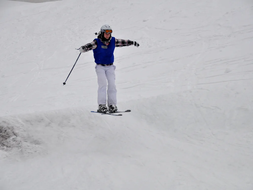 Skifahrerin in weißer Hose auf der Piste.
